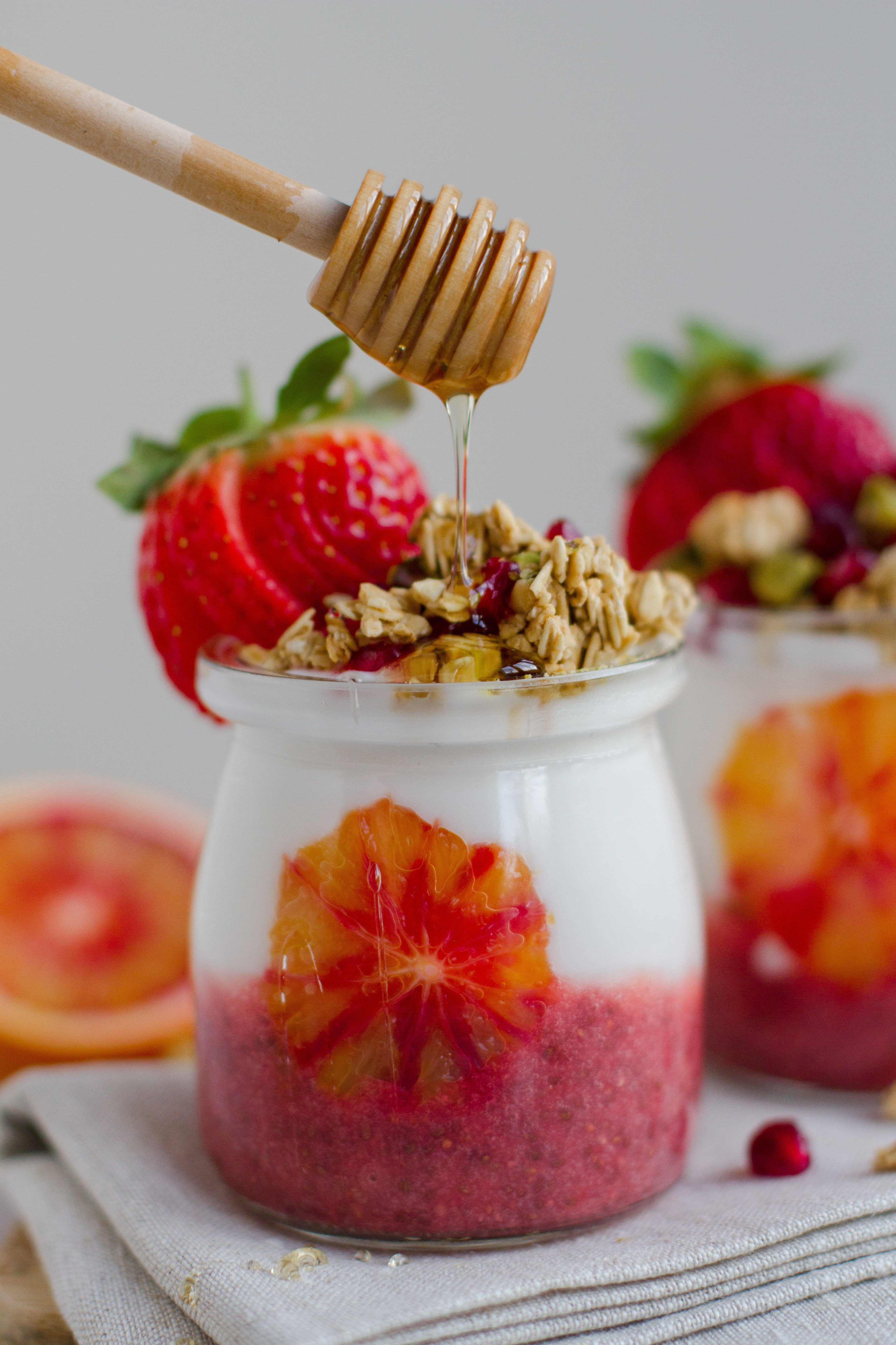 blood orange and strawberry chia pudding parfat jar with coconut oyugrt, granola and agave syrup. vegan recipe
