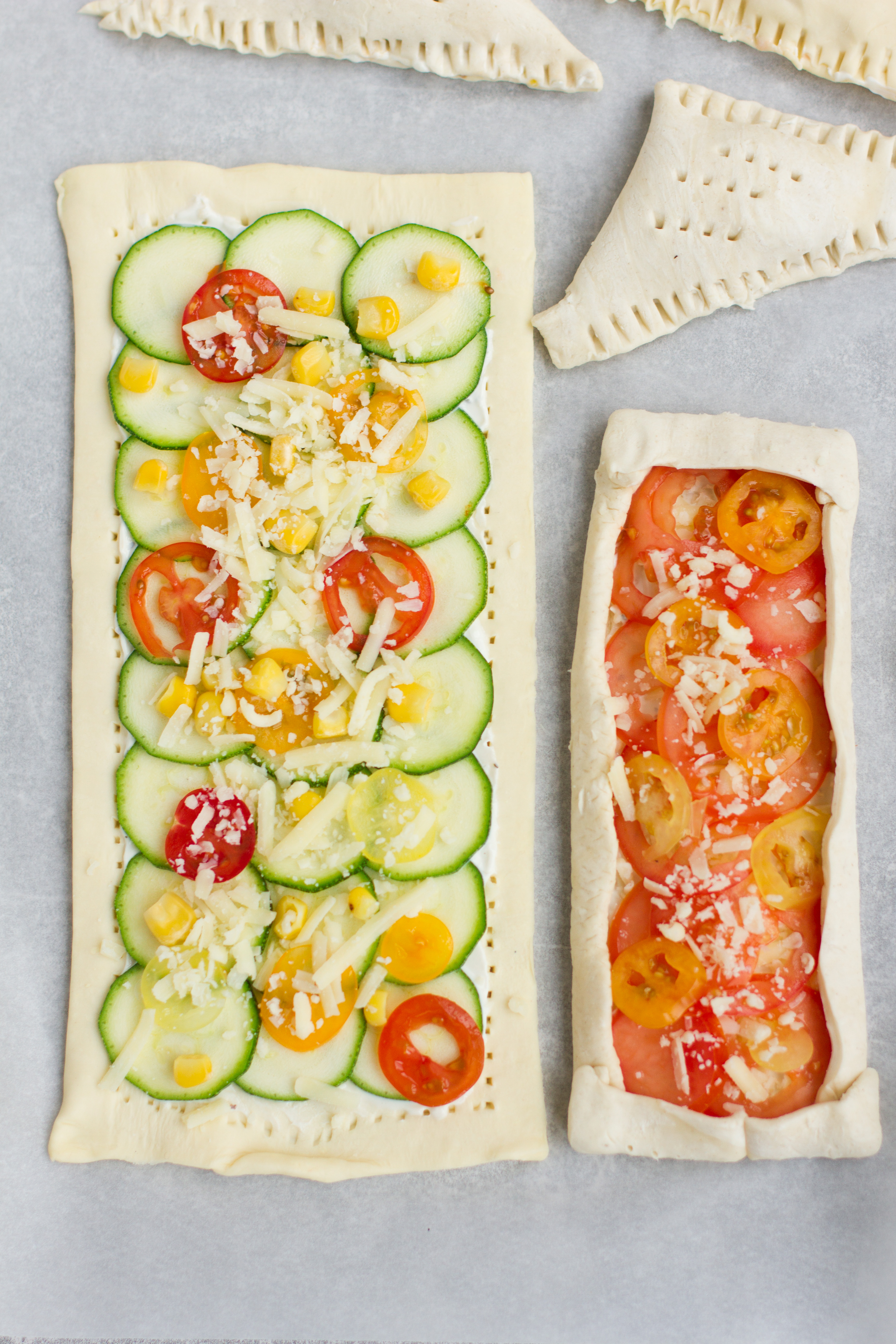Vegetarian vegan valentines puff pastry pizzas with rainbow tomatoes and courgette, olives, sweetcorn, peas and feta