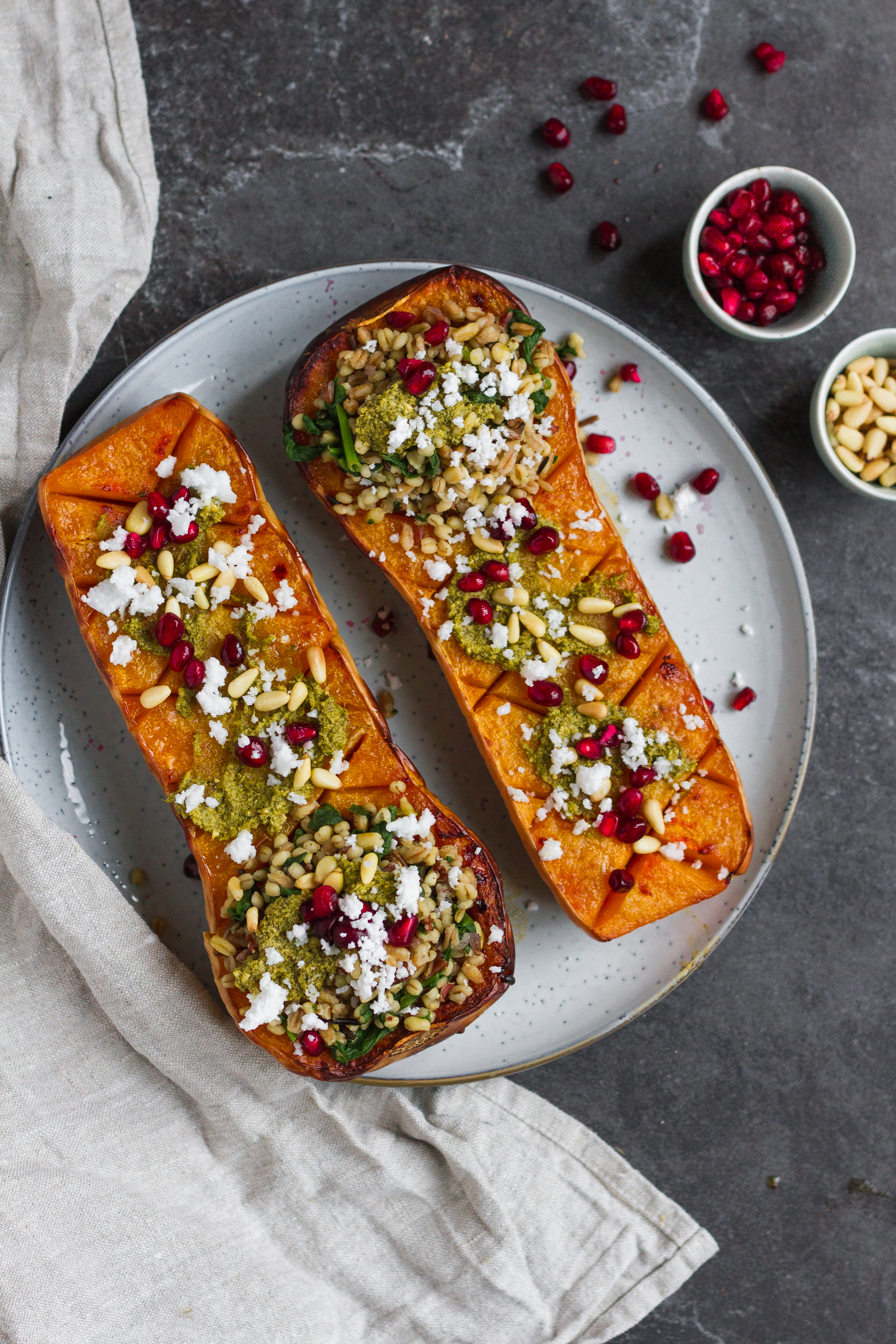 Vegetarian roasted butternut squash with pistachio pesto, grains, pine nuts, pomegranate and feta. A delicious fall recipe, perfect vegetarian Thanksgiving recipe.
