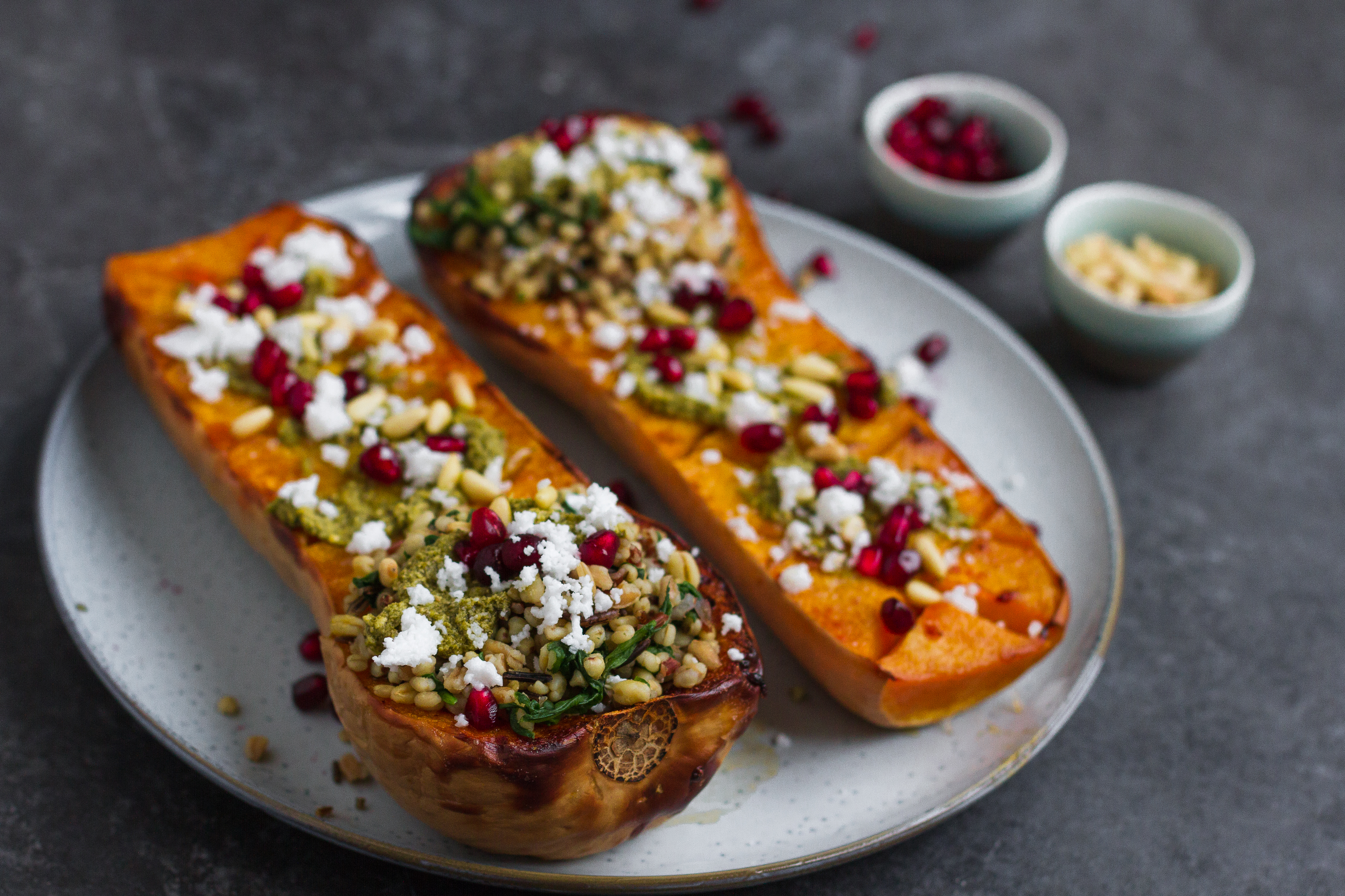 Vegetarian roasted butternut squash with pistachio pesto, grains, pine nuts, pomegranate and feta. A delicious fall recipe, perfect vegetarian Thanksgiving recipe.