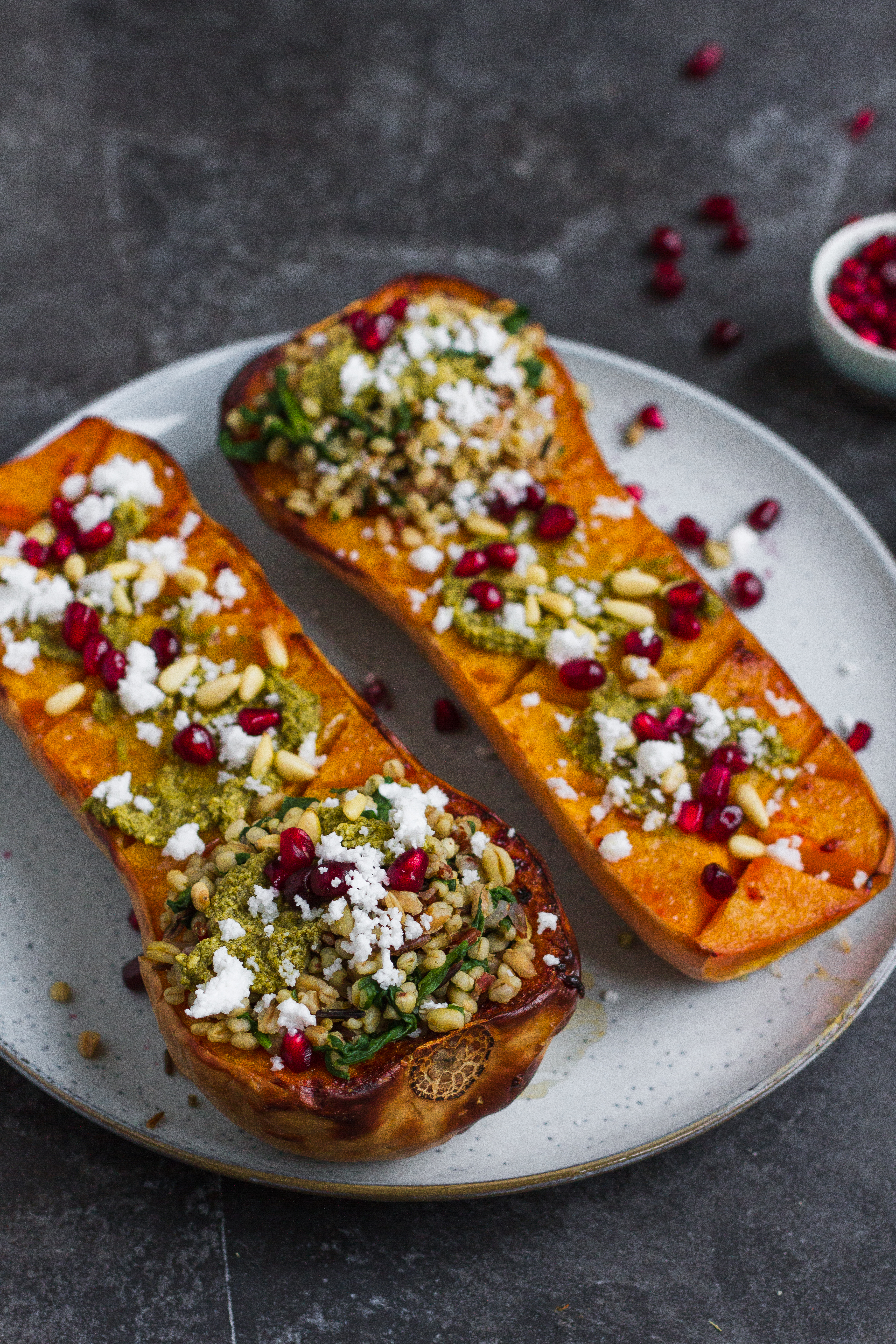 Vegetarian roasted butternut squash with pistachio pesto, grains, pine nuts, pomegranate and feta. A delicious fall recipe, perfect vegetarian Thanksgiving recipe.