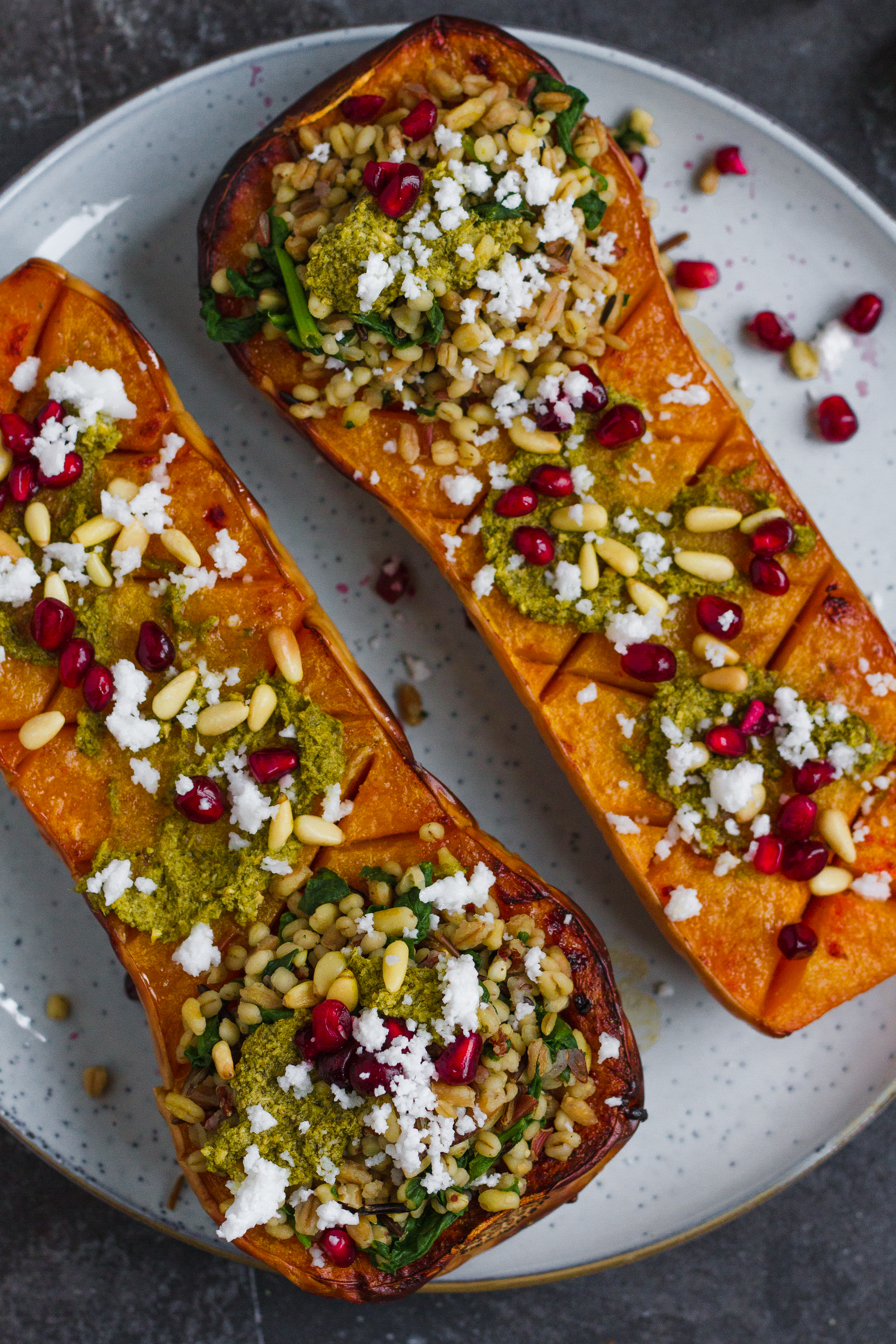 Vegetarian roasted butternut squash with pistachio pesto, grains, pine nuts, pomegranate and feta. A delicious fall recipe, perfect vegetarian Thanksgiving recipe.