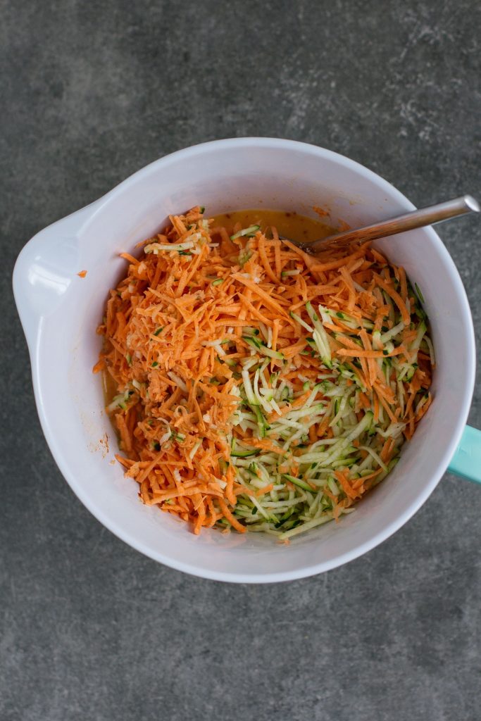 mixing courgette and sweet potato in large bowl with eggs