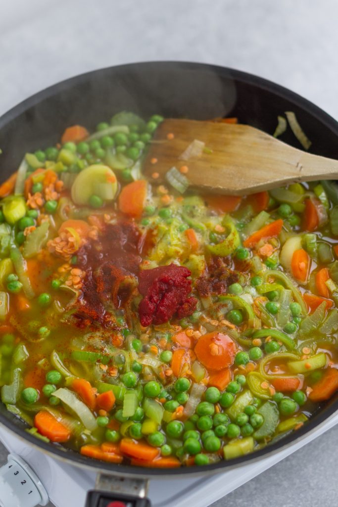 tomato paste added to sauteed vegetables in a large frying pan