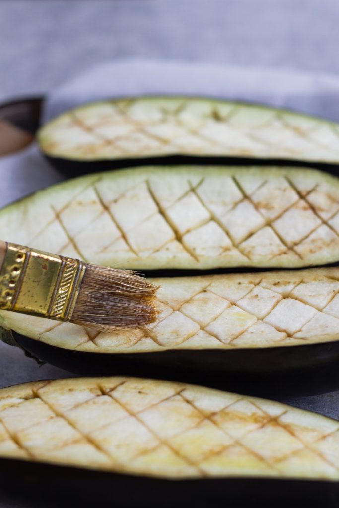 brushing scored eggplant with olive oil